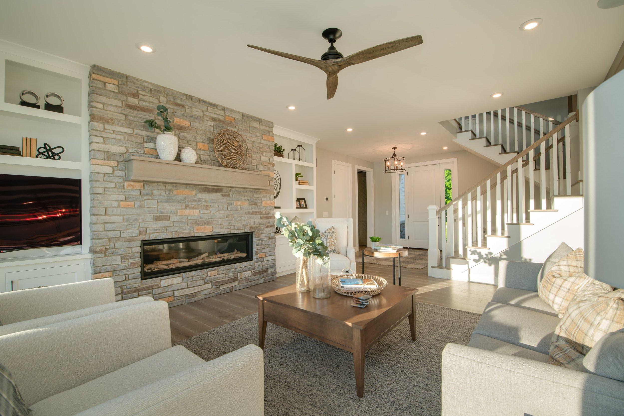 Freshly cleaned living room with a stone fireplace and open staircase, house cleaning in Denver Metro